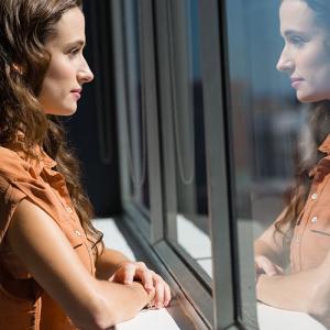 Lady starting at her reflection in glass