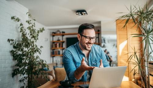 Male sitting at a desk facing his laptop whilst speaking on a virtual call