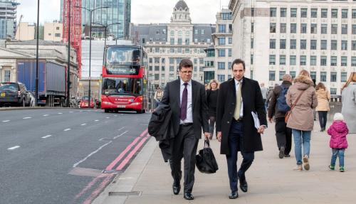 Two coworkers dressed in corporate wear walking along street