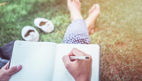 Female sitting outside writing in journal